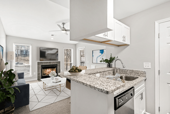 A modern kitchen with a fireplace and a blue sofa at Paces Pointe Apartment Homes, Matthews, NC
